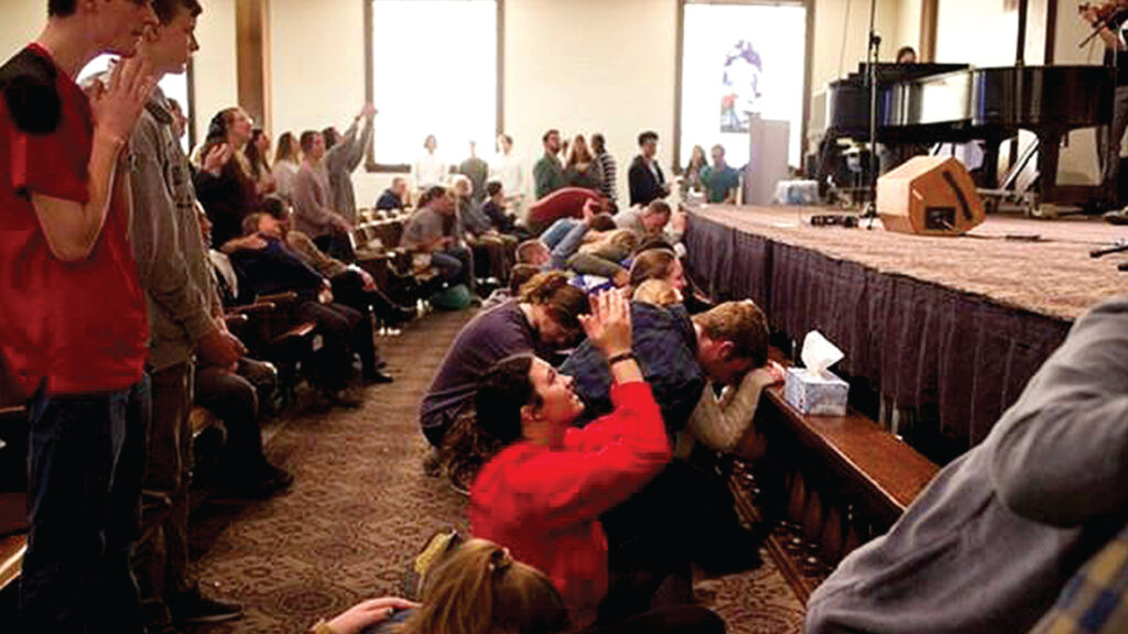 Students kneel and pray at the altar at Hughes Auditorium at Asbury University in Wilmore, Kentucky. (Photo courtesy of The Asbury Collegian.)